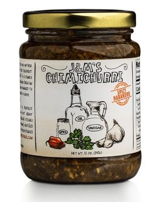 This jar features J&M's Chimichurri labeled with a "Spicy Habanero" badge. The design showcases a handcrafted appeal, highlighted by hand-drawn illustrations of the main ingredients like oil, vinegar, spice, garlic, and notably, a habanero pepper, indicating the spicy character of this variant. The badge, in bright red with the label "Spicy Habanero," signals that this edition of chimichurri sauce promises an intense heat, ideal for those who appreciate a fiery kick in their dishes. The product has a net weight of 12 oz (340g). Like the other versions, the design underscores an authentic and traditional feel, suggesting that the sauce is crafted with care. The inclusion of the habanero pepper illustration hints at an elevated level of spiciness for those seeking a bolder flavor experience.