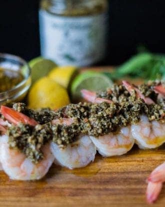 Tender shrimp skewers, generously coated with J&M's rich Chimichurri, paired with fresh citrus on a rustic wooden board. A feast for both eyes and palate.